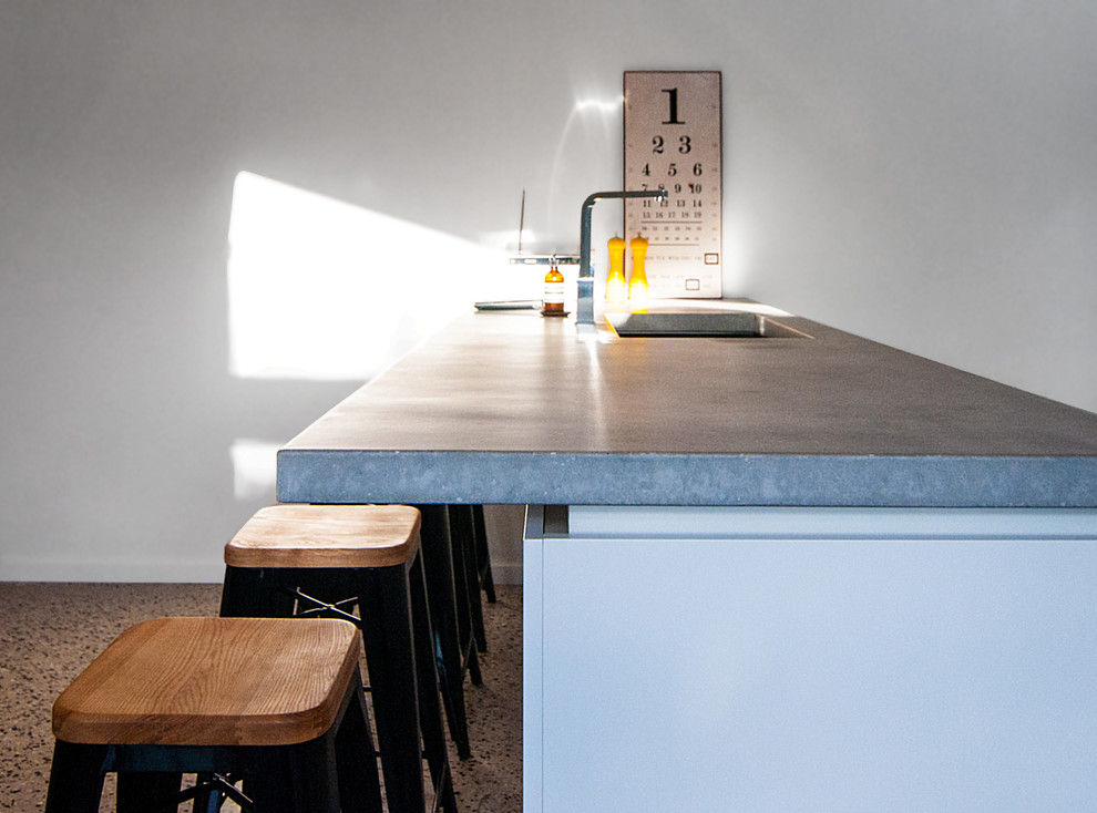 Inspiration for a contemporary galley concrete floor eat-in kitchen remodel in Melbourne with white cabinets, concrete countertops, an island and an integrated sink