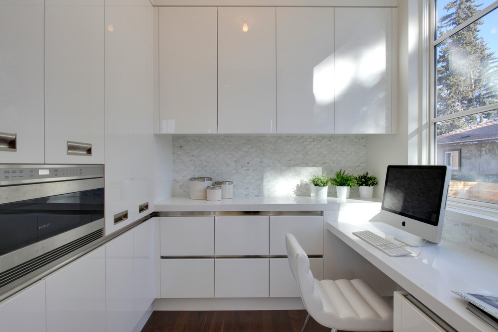 Moderne Küche mit flächenbündigen Schrankfronten, weißen Schränken, Küchenrückwand in Weiß und Küchengeräten aus Edelstahl in Calgary