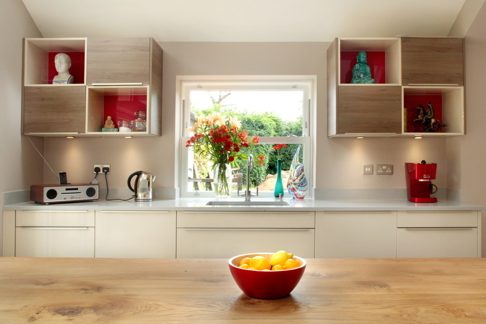 Imagen de cocina actual con fregadero bajoencimera, armarios con paneles lisos, puertas de armario beige y una isla