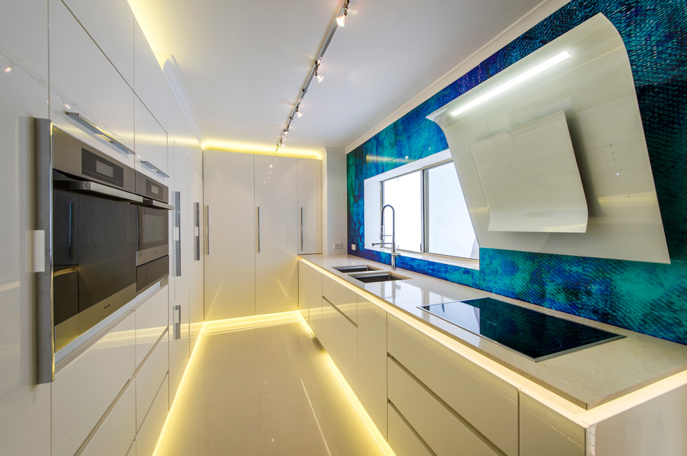 Small contemporary galley enclosed kitchen in Perth with a double-bowl sink, flat-panel cabinets, white cabinets, blue splashback, integrated appliances and no island.
