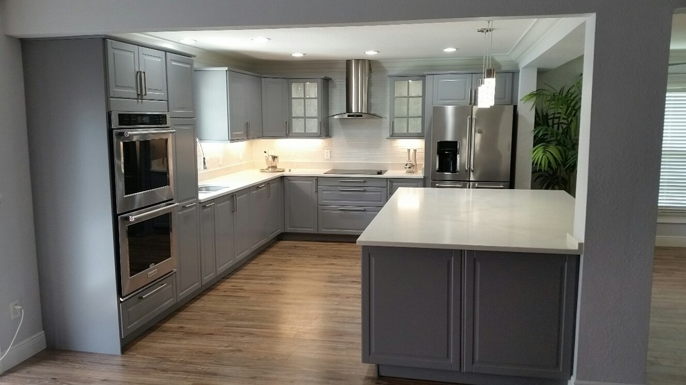 Exempel på ett stort modernt vit vitt l-kök, med en undermonterad diskho, luckor med upphöjd panel, grå skåp, bänkskiva i koppar, rostfria vitvaror, mellanmörkt trägolv, en köksö och brunt golv
