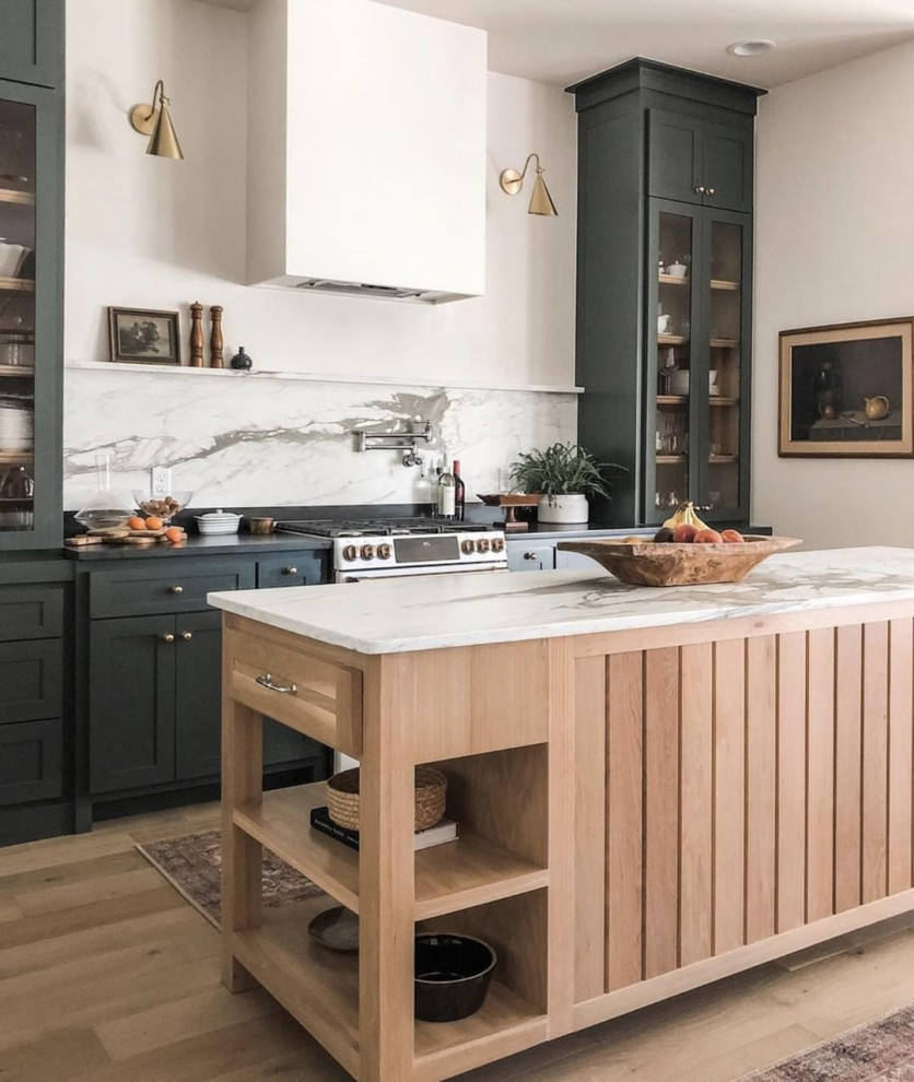 Bild på ett mellanstort funkis svart linjärt svart kök med öppen planlösning, med en undermonterad diskho, skåp i shakerstil, gröna skåp, bänkskiva i kvartsit, vitt stänkskydd, stänkskydd i marmor, rostfria vitvaror, ljust trägolv, en köksö och brunt golv