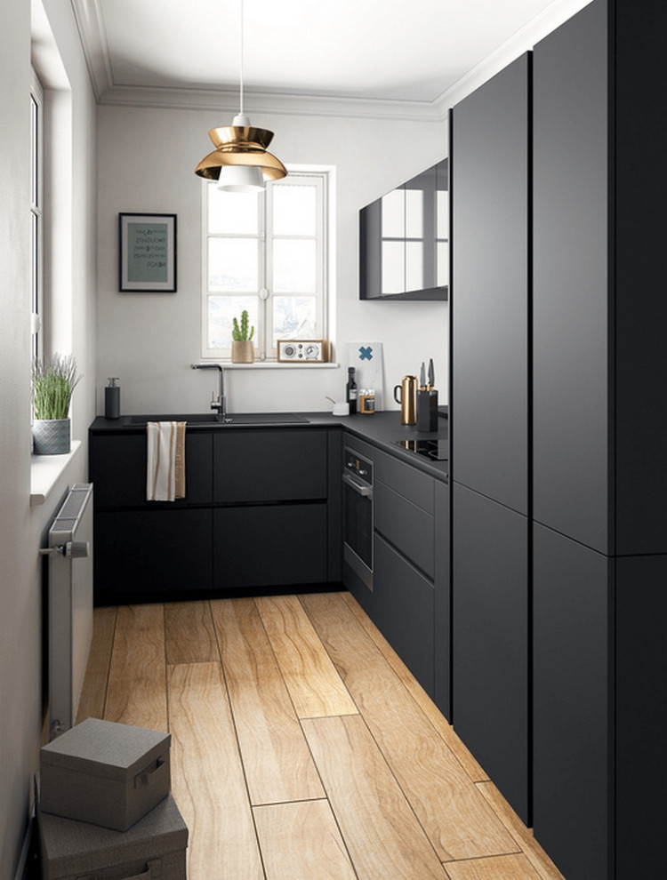 Foto på ett avskilt, litet funkis svart l-kök, med en undermonterad diskho, släta luckor, svarta skåp, bänkskiva i kvartsit, svarta vitvaror, ljust trägolv och brunt golv