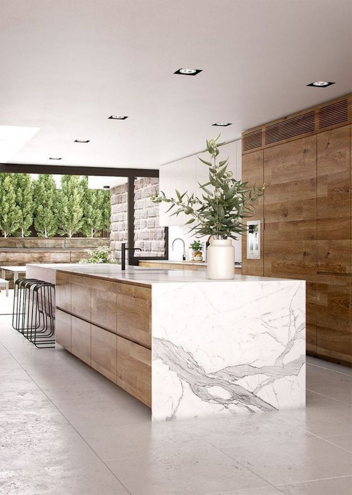 Immagine di una grande cucina design con lavello sottopiano, ante lisce, ante in legno chiaro, top in marmo, elettrodomestici in acciaio inossidabile, pavimento in cementine, pavimento grigio e top bianco
