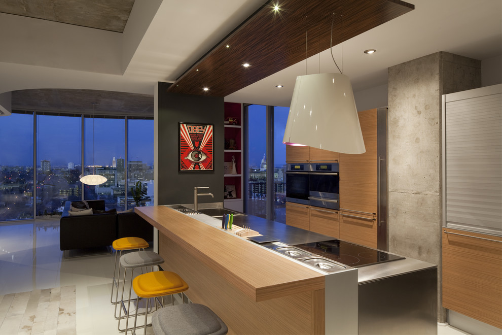 Moderne Küche mit flächenbündigen Schrankfronten, hellen Holzschränken und Küchengeräten aus Edelstahl in Austin