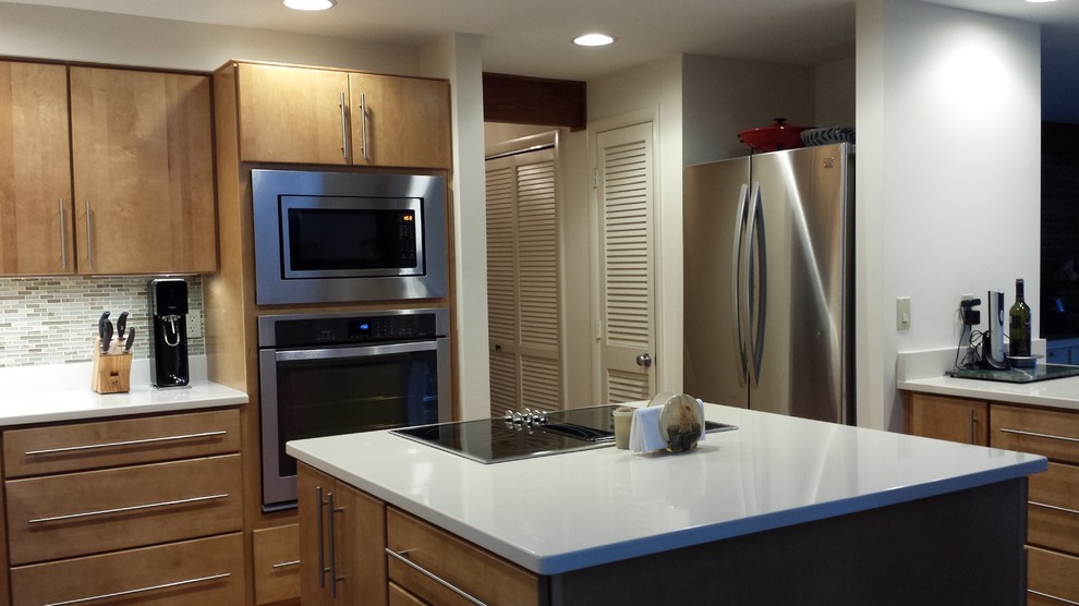 Exempel på ett modernt kök, med en undermonterad diskho, släta luckor, skåp i ljust trä, bänkskiva i kvartsit, brunt stänkskydd, stänkskydd i glaskakel och rostfria vitvaror