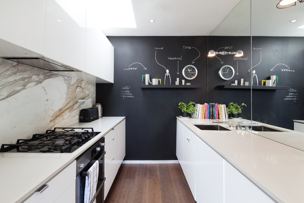 Zweizeilige Moderne Schmale Küche mit flächenbündigen Schrankfronten, weißen Schränken, Küchenrückwand in Weiß, Rückwand aus Stein und braunem Holzboden in London