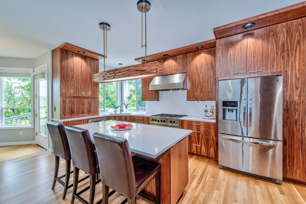 Inspiration for a large contemporary l-shaped light wood floor and brown floor open concept kitchen remodel in Portland with an undermount sink, flat-panel cabinets, dark wood cabinets, quartz countertops, white backsplash, quartz backsplash, stainless steel appliances, an island and white countertops