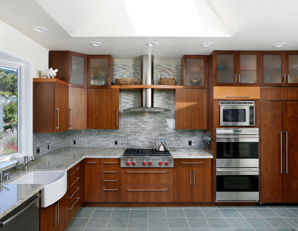 Modelo de cocinas en U contemporáneo con armarios con paneles lisos, puertas de armario de madera en tonos medios y salpicadero con mosaicos de azulejos