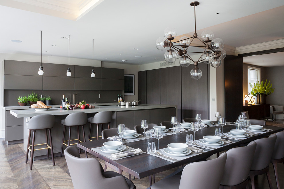 Large contemporary kitchen/diner in London with a submerged sink, flat-panel cabinets, grey cabinets, quartz worktops, grey splashback, black appliances, dark hardwood flooring and an island.