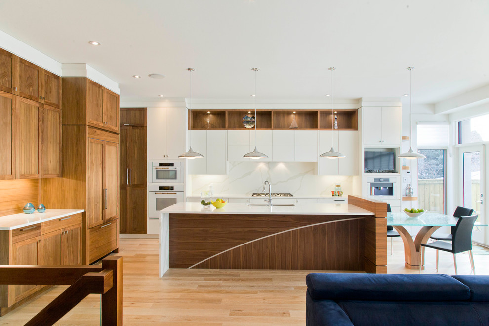 Offene, Große Moderne Küche in L-Form mit Unterbauwaschbecken, flächenbündigen Schrankfronten, weißen Schränken, Küchengeräten aus Edelstahl, hellem Holzboden und Kücheninsel in Calgary
