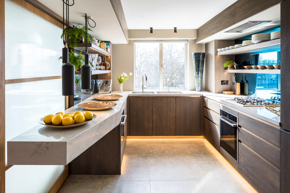 Photo of a contemporary u-shaped kitchen in London with a double-bowl sink, flat-panel cabinets, marble worktops, blue splashback, glass sheet splashback, stainless steel appliances, beige floors, grey worktops, dark wood cabinets and no island.