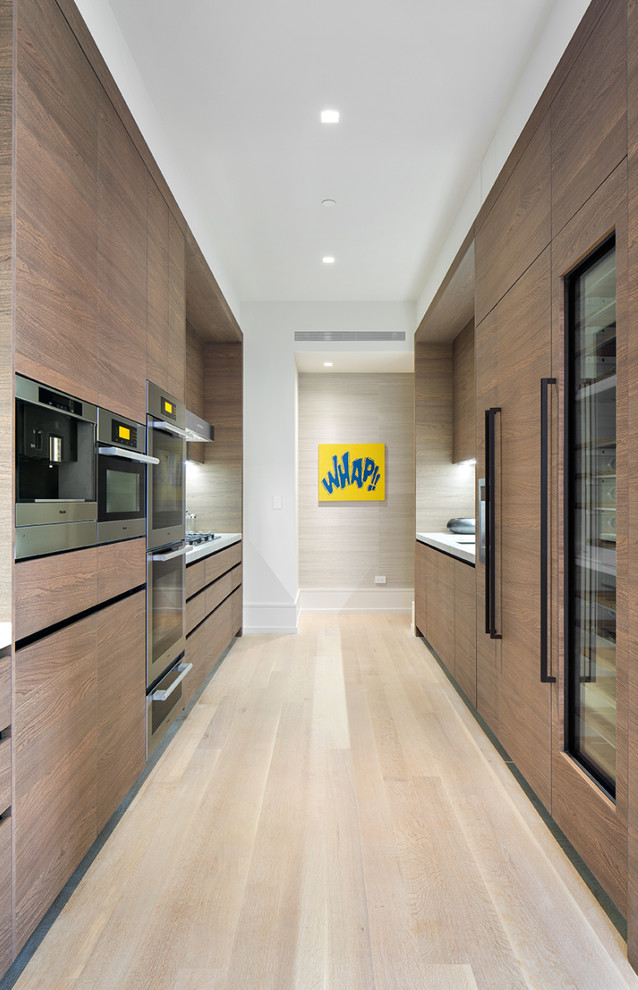 Design ideas for a contemporary galley enclosed kitchen in New York with flat-panel cabinets, dark wood cabinets, stainless steel appliances, light hardwood flooring and no island.