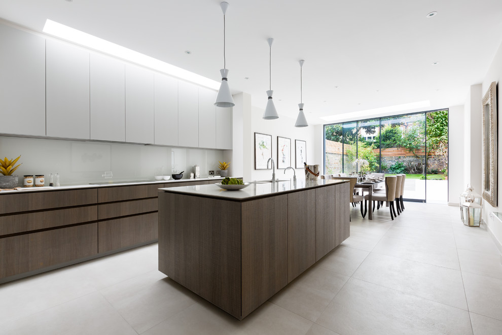 Offene Moderne Küche mit flächenbündigen Schrankfronten, weißen Schränken, Küchenrückwand in Weiß, Glasrückwand und Kücheninsel in London