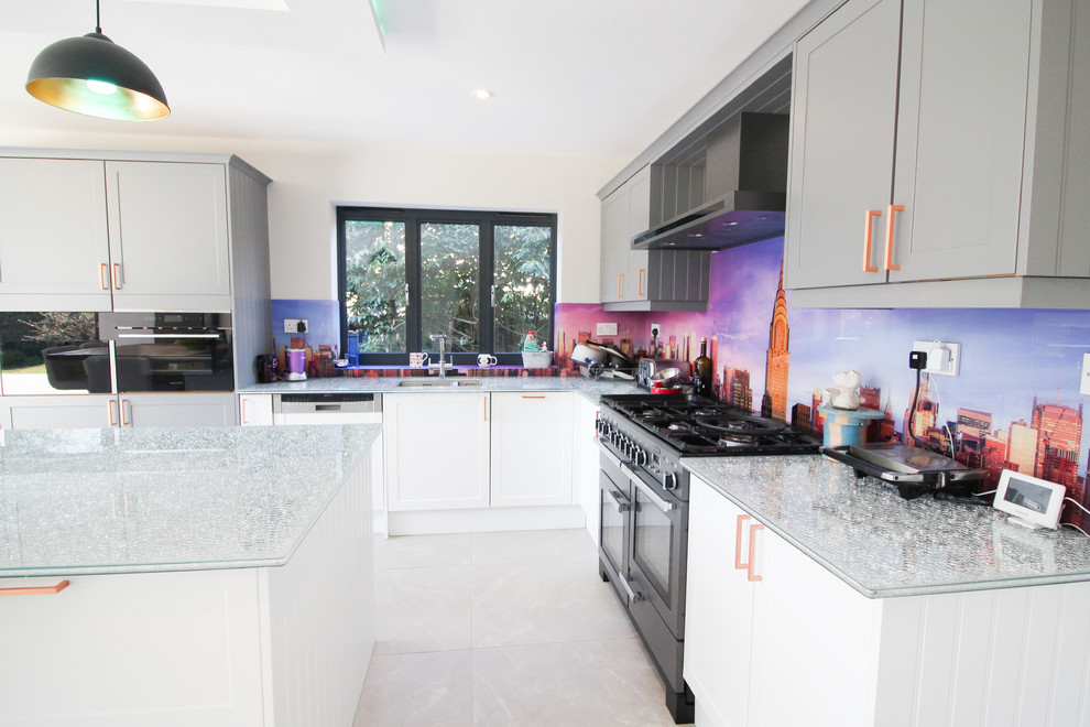 Design ideas for an expansive contemporary u-shaped open plan kitchen in London with an integrated sink, shaker cabinets, white cabinets, glass worktops, multi-coloured splashback, glass sheet splashback, black appliances, ceramic flooring, an island, grey floors and green worktops.