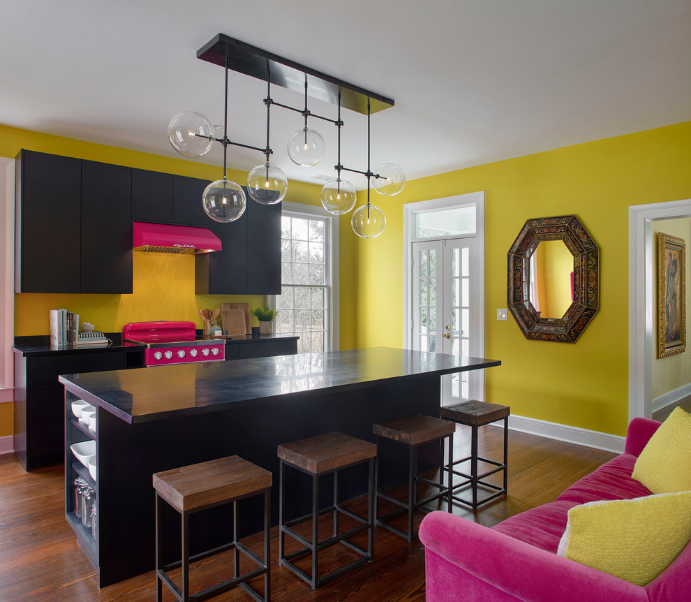 Zweizeilige Moderne Küche mit flächenbündigen Schrankfronten, schwarzen Schränken, bunten Elektrogeräten, dunklem Holzboden, Kücheninsel, braunem Boden und schwarzer Arbeitsplatte in Atlanta