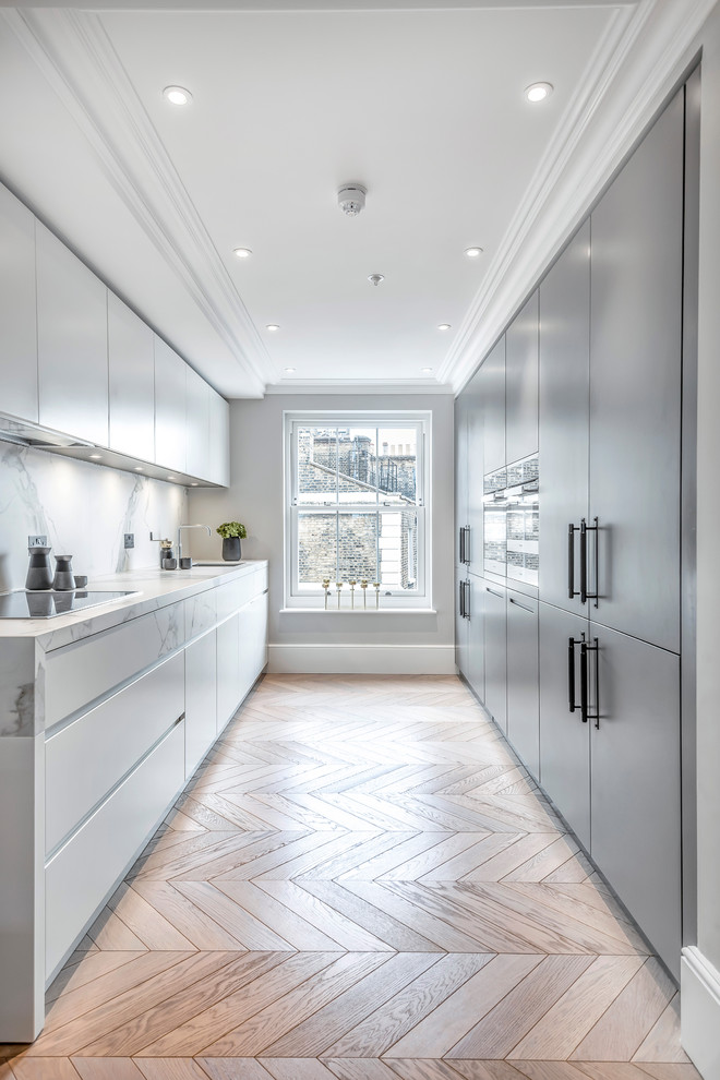 Inspiration for a contemporary galley medium tone wood floor and brown floor enclosed kitchen remodel in London with gray cabinets, white backsplash, white countertops and flat-panel cabinets