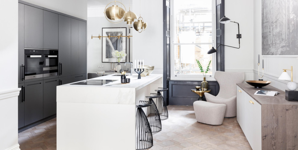 Klassische Küche mit flächenbündigen Schrankfronten, grauen Schränken, Küchenrückwand in Weiß, braunem Holzboden, braunem Boden und weißer Arbeitsplatte in London