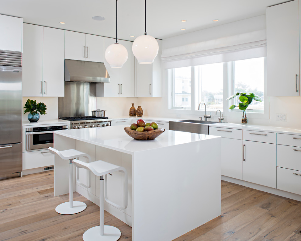 Inspiration for a large contemporary l-shaped open plan kitchen in Other with flat-panel cabinets, white cabinets, engineered stone countertops, white splashback, an island, a belfast sink, stainless steel appliances and medium hardwood flooring.