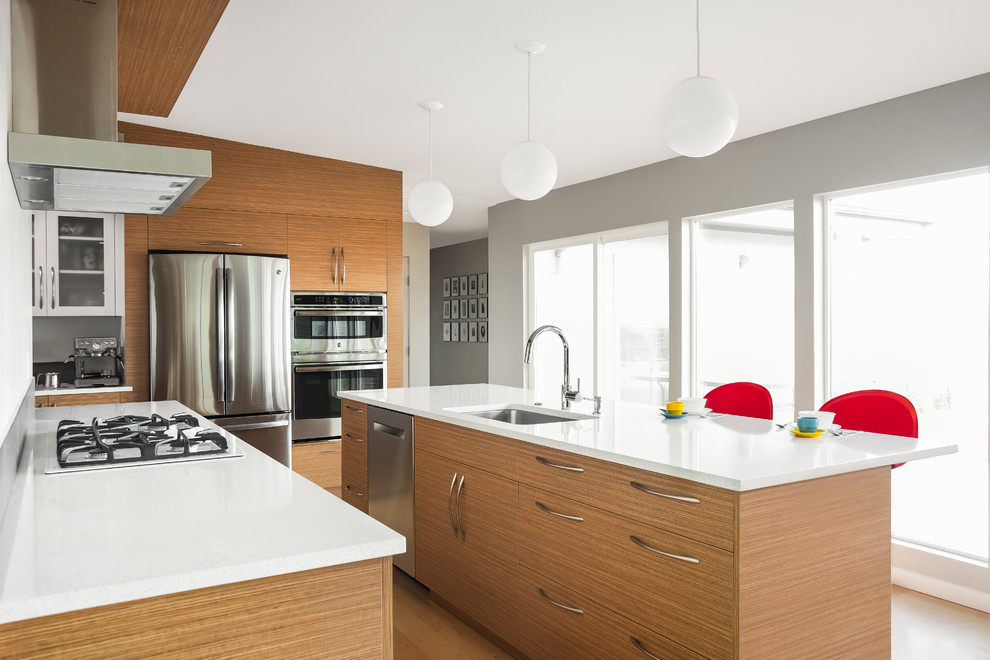 Moderne Küche in L-Form mit Unterbauwaschbecken, flächenbündigen Schrankfronten, hellbraunen Holzschränken, Küchengeräten aus Edelstahl, braunem Holzboden und Kücheninsel in Boise