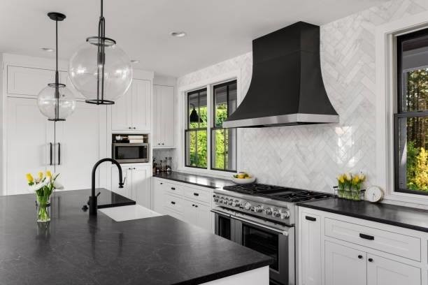 Eat-in kitchen - large transitional u-shaped dark wood floor and brown floor eat-in kitchen idea in Philadelphia with a farmhouse sink, recessed-panel cabinets, white cabinets, soapstone countertops, white backsplash, marble backsplash, paneled appliances, an island and black countertops