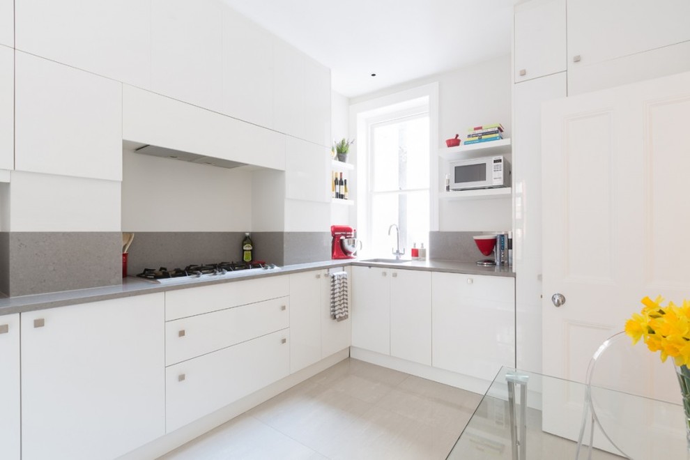 Moderne Wohnküche ohne Insel in L-Form mit flächenbündigen Schrankfronten, weißen Schränken und Küchenrückwand in Grau in London