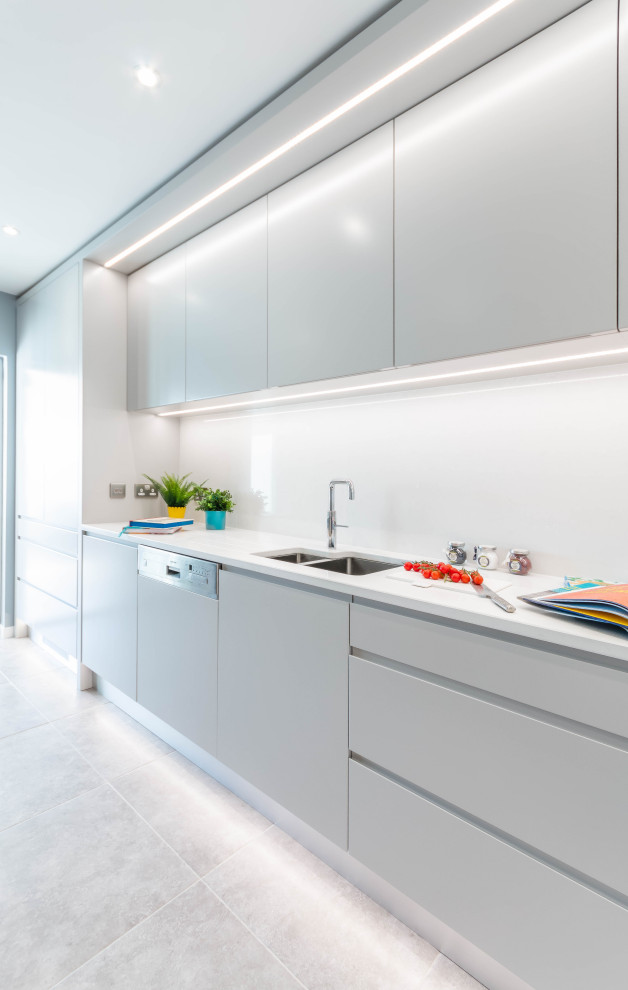 Medium sized contemporary l-shaped kitchen/diner in Dublin with flat-panel cabinets, grey cabinets, quartz worktops, white splashback, stainless steel appliances, porcelain flooring, grey floors and white worktops.