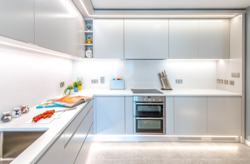 Inspiration for a medium sized contemporary l-shaped kitchen/diner in Dublin with a submerged sink, flat-panel cabinets, grey cabinets, quartz worktops, white splashback, stainless steel appliances, porcelain flooring, grey floors and white worktops.