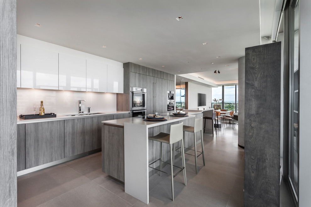 Immagine di una cucina contemporanea con lavello sottopiano, ante lisce, ante grigie, elettrodomestici in acciaio inossidabile, pavimento grigio e top bianco