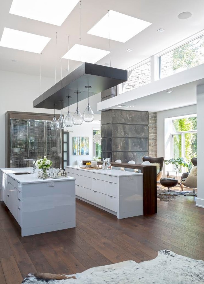 Photo of a contemporary galley open plan kitchen in Other with a submerged sink, flat-panel cabinets, white cabinets, dark hardwood flooring and multiple islands.