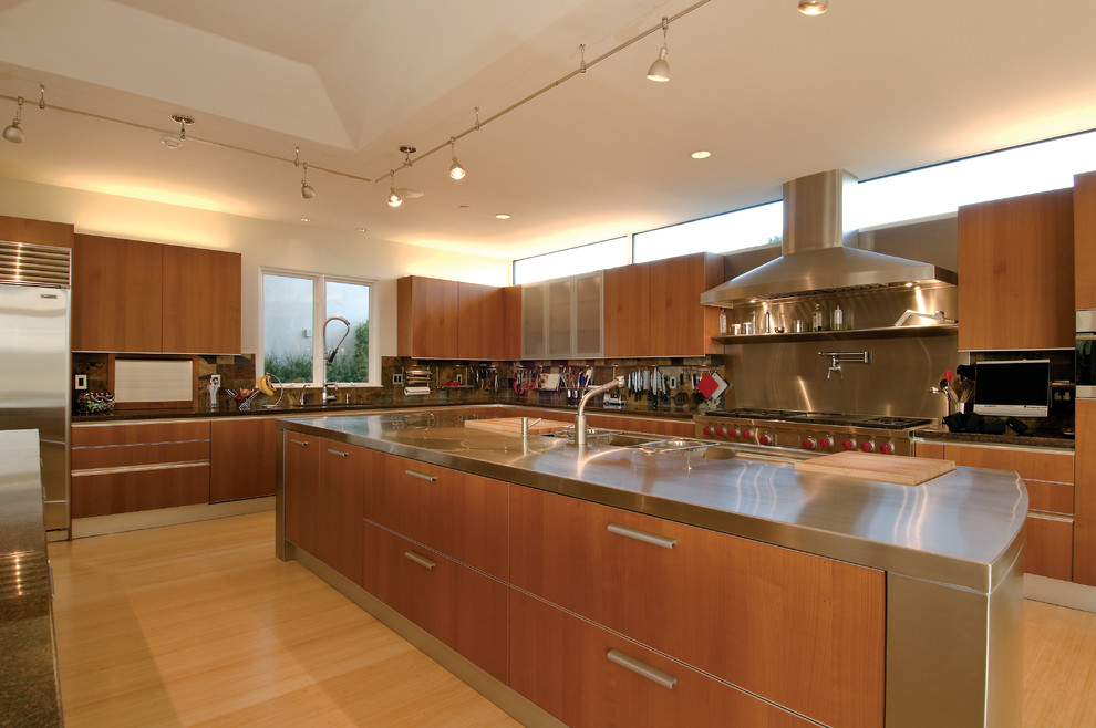 Example of a large trendy l-shaped bamboo floor eat-in kitchen design in San Francisco with a double-bowl sink, flat-panel cabinets, medium tone wood cabinets, stainless steel countertops, stainless steel appliances and two islands