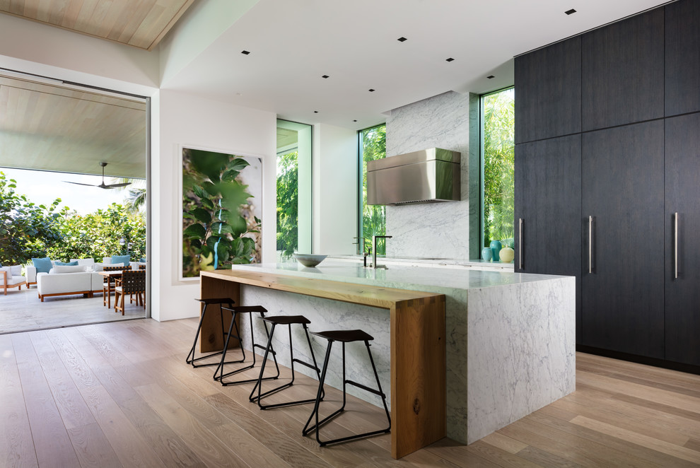 Foto di una cucina contemporanea con ante lisce, ante nere, paraspruzzi bianco, pavimento in legno massello medio, pavimento marrone e top bianco
