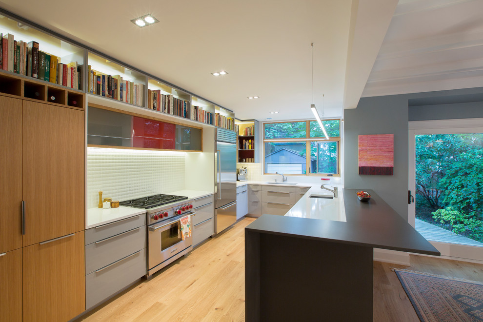 Example of a large trendy u-shaped light wood floor eat-in kitchen design in Toronto with flat-panel cabinets, gray cabinets, quartz countertops, white backsplash, porcelain backsplash, stainless steel appliances and a peninsula