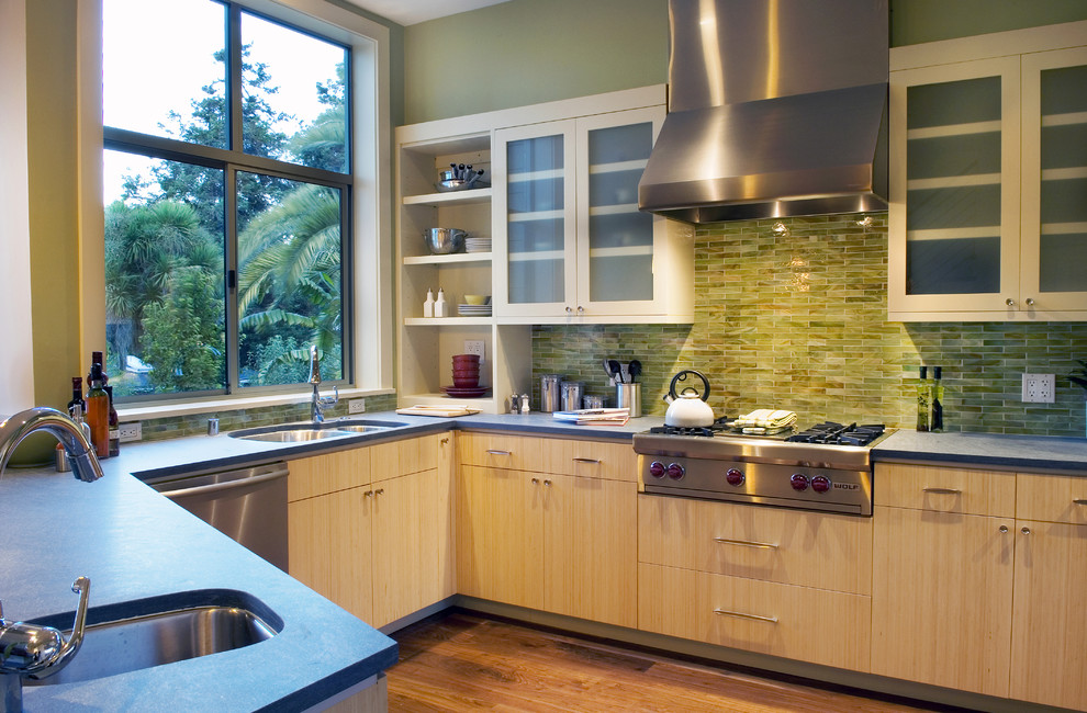 サンフランシスコにあるコンテンポラリースタイルのおしゃれなキッチン (ダブルシンク、フラットパネル扉のキャビネット、淡色木目調キャビネット、緑のキッチンパネル、シルバーの調理設備) の写真