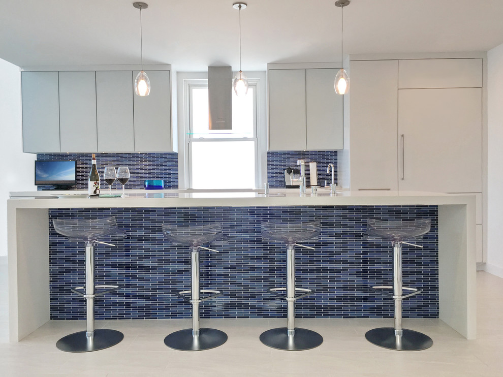 Foto på ett funkis linjärt kök, med släta luckor, vita skåp, blått stänkskydd, en köksö, en undermonterad diskho, bänkskiva i kvarts, stänkskydd i mosaik och integrerade vitvaror