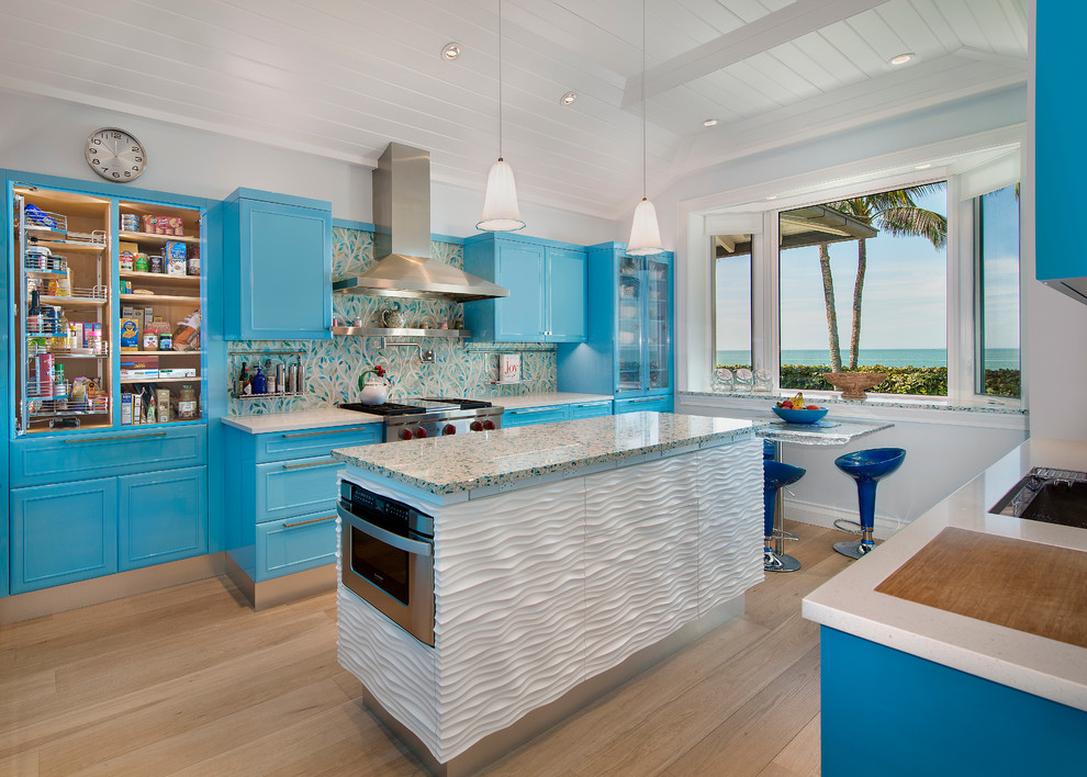 На фото: п-образная кухня в морском стиле с фасадами с утопленной филенкой, синими фасадами, разноцветным фартуком, фартуком из плитки мозаики, техникой из нержавеющей стали, светлым паркетным полом и островом с