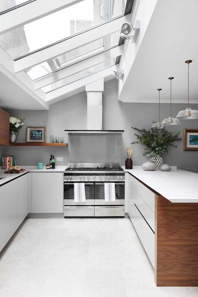 На фото: п-образная кухня в современном стиле с плоскими фасадами, белыми фасадами и фартуком из стекла