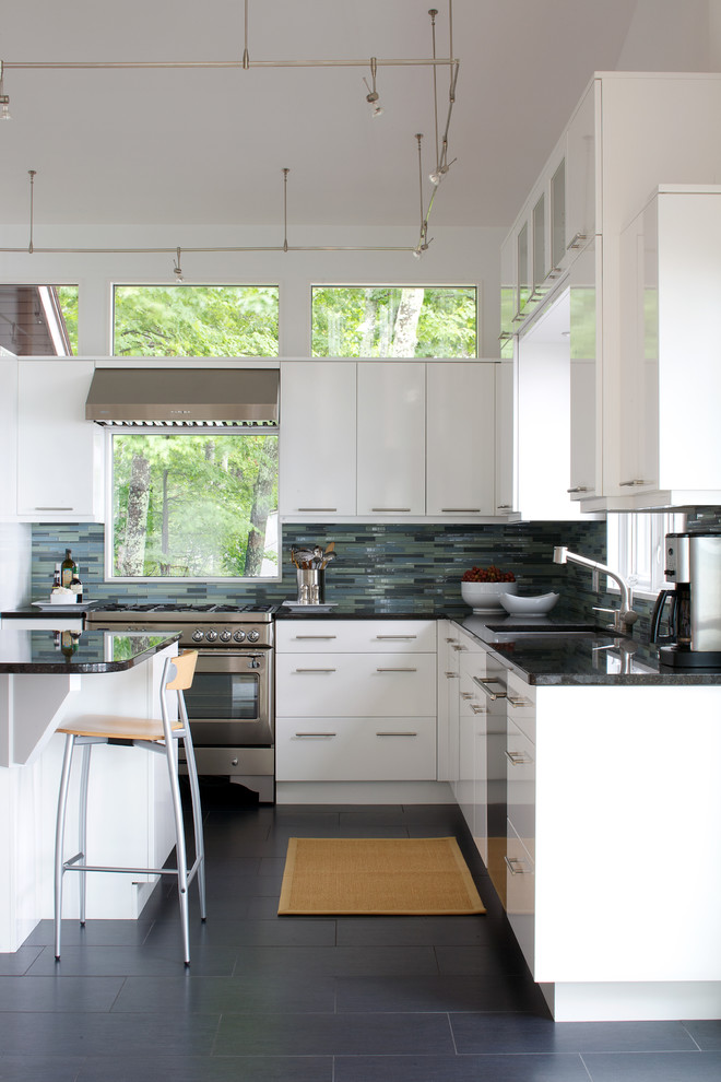 Example of a trendy l-shaped kitchen design in Other with stainless steel appliances, an undermount sink, flat-panel cabinets, white cabinets, blue backsplash and matchstick tile backsplash