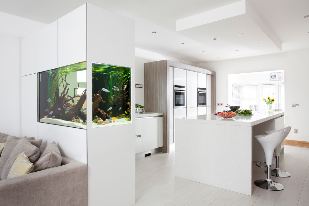 Cette image montre une cuisine design avec un placard à porte plane, des portes de placard blanches et un électroménager en acier inoxydable.