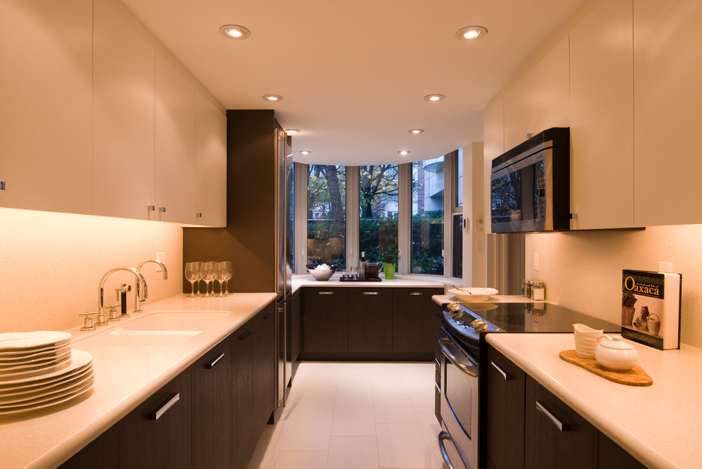 Cette image montre une cuisine parallèle design fermée avec un évier 2 bacs, un placard à porte plane et des portes de placard blanches.