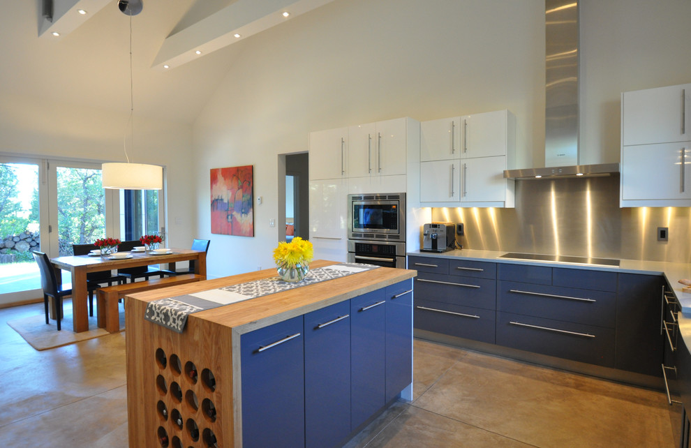 アルバカーキにある広いコンテンポラリースタイルのおしゃれなキッチン (エプロンフロントシンク、フラットパネル扉のキャビネット、青いキャビネット、メタリックのキッチンパネル、シルバーの調理設備、コンクリートの床) の写真