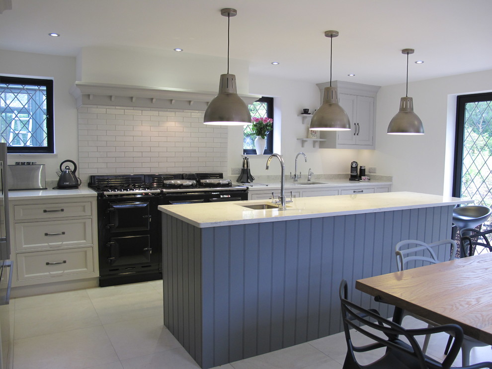 Inspiration for a large contemporary u-shaped kitchen/diner in Surrey with a single-bowl sink, recessed-panel cabinets, grey cabinets, composite countertops, white splashback, metro tiled splashback, stainless steel appliances, porcelain flooring and an island.
