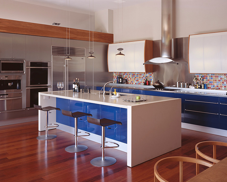 Пример оригинального дизайна: большая угловая кухня-гостиная в современном стиле с плоскими фасадами, синими фасадами, столешницей из кварцевого агломерата, разноцветным фартуком, фартуком из керамической плитки, техникой из нержавеющей стали, паркетным полом среднего тона, островом, коричневым полом и белой столешницей