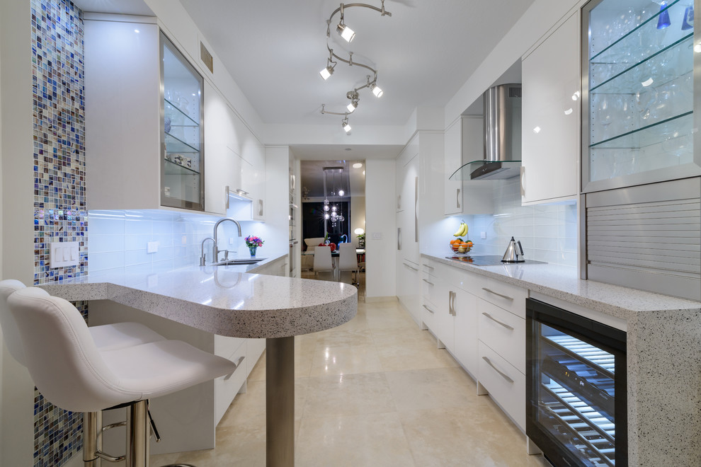 Inspiration for a mid-sized contemporary galley beige floor and porcelain tile enclosed kitchen remodel in Miami with an undermount sink, flat-panel cabinets, white cabinets, quartz countertops, white backsplash, glass tile backsplash, white appliances and no island