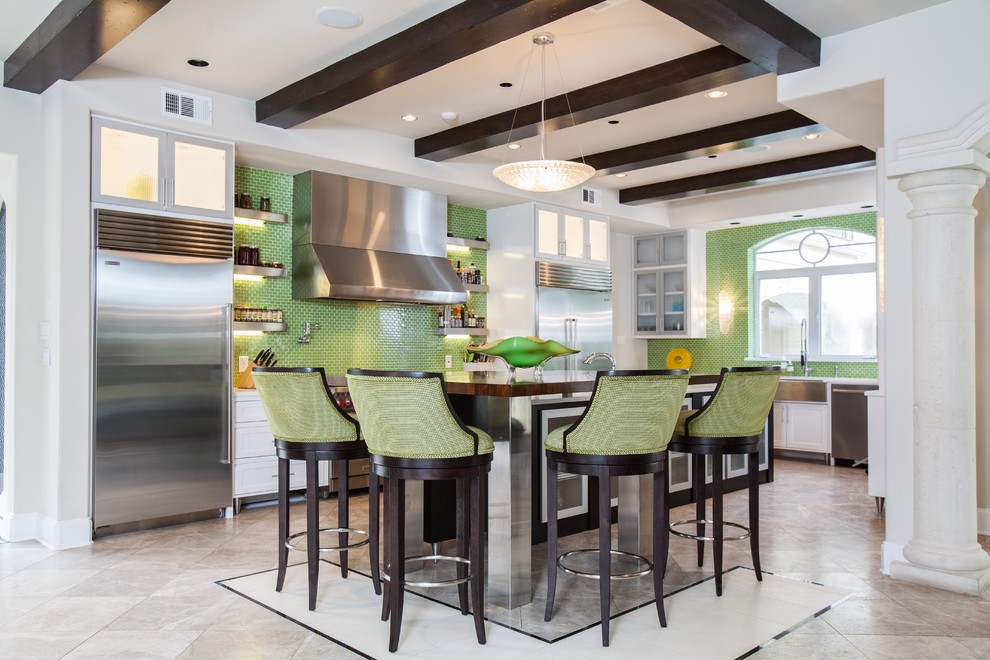 Medium sized contemporary l-shaped kitchen/diner in Houston with a belfast sink, glass-front cabinets, white cabinets, engineered stone countertops, green splashback, mosaic tiled splashback, stainless steel appliances, limestone flooring and an island.