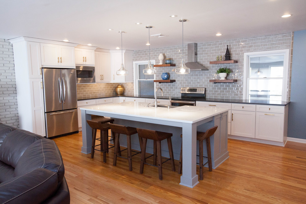 Open concept kitchen - large contemporary l-shaped medium tone wood floor open concept kitchen idea in Philadelphia with a farmhouse sink, shaker cabinets, white cabinets, quartzite countertops, gray backsplash, subway tile backsplash, stainless steel appliances and an island