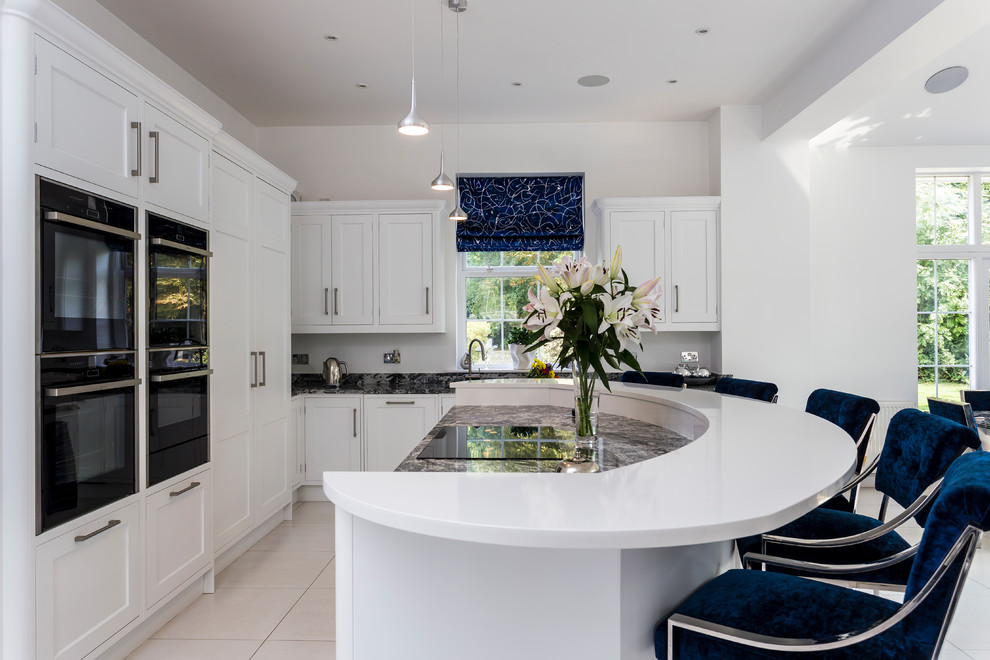 Inspiration for a classic l-shaped open plan kitchen in Hertfordshire with shaker cabinets, white cabinets, integrated appliances, an island, beige floors and grey worktops.