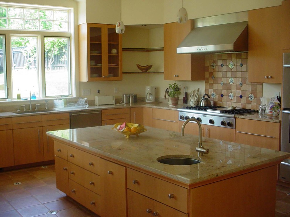 Inredning av ett klassiskt kök, med en undermonterad diskho, släta luckor, skåp i ljust trä, granitbänkskiva, flerfärgad stänkskydd, stänkskydd i terrakottakakel och integrerade vitvaror