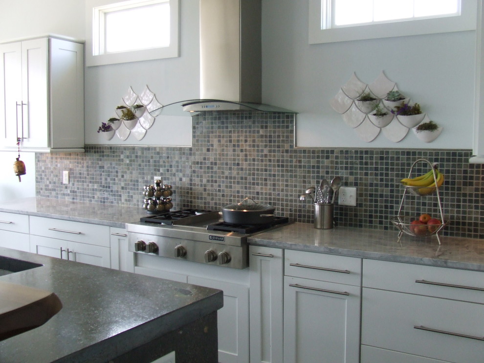Bild på ett funkis kök, med skåp i shakerstil, vita skåp, bänkskiva i betong, flerfärgad stänkskydd, stänkskydd i keramik, rostfria vitvaror och en köksö