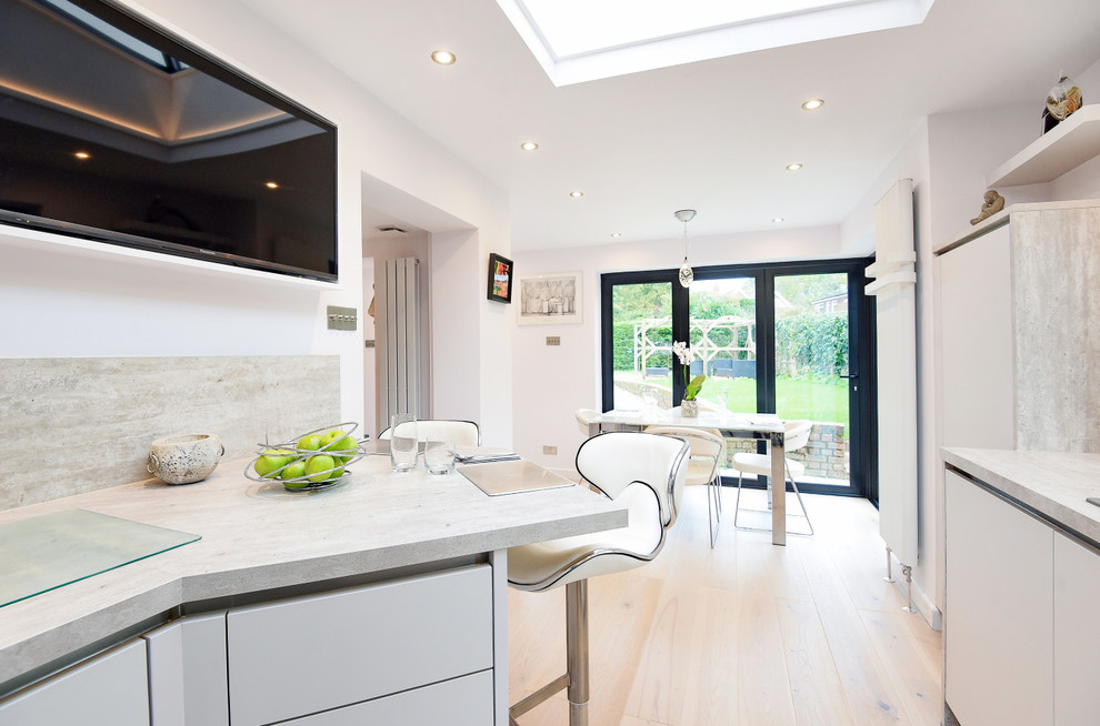 This is an example of a small contemporary u-shaped kitchen/diner in Berkshire with a built-in sink, flat-panel cabinets, grey cabinets, laminate countertops, grey splashback, medium hardwood flooring, no island and white floors.